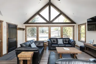 a living room with leather furniture and a large window at Summit View in Valemount