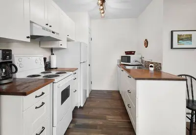 a kitchen with white appliances and a wooden floor at Mountain Gate - Pet Friendly 2BR w Mountain Views and open hot tub in Canmore