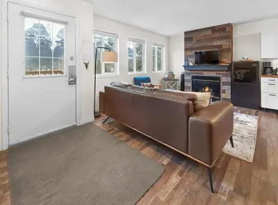 a living room with a brown couch and a fireplace at Mountain Gate - Pet Friendly 2BR w Mountain Views and open hot tub in Canmore
