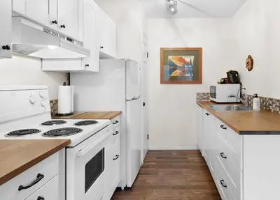 a kitchen with white cabinets and a white stove top oven at Mountain Gate - Pet Friendly 2BR w Mountain Views and open hot tub in Canmore