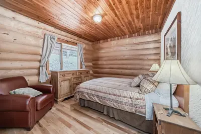 a log cabin bedroom with a bed and a chair at Terracana Ranch Resort in Tete Jaune Cache