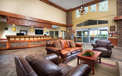 a living room with leather furniture and a bar at Gold Eagle Lodge in North Battleford