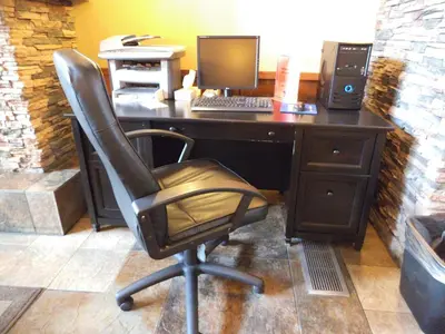 a desk with a computer monitor and a chair at Gold Eagle Lodge in North Battleford