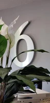 a white number on a wall with a plant at Motel 6 Brooks AB in Brooks