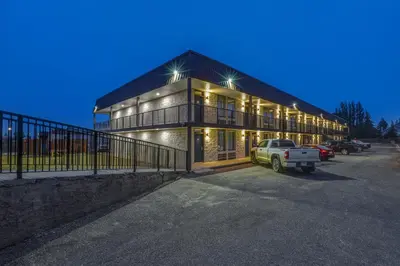 a house with a car parked in a parking lot at Motel 6 Brooks AB in Brooks