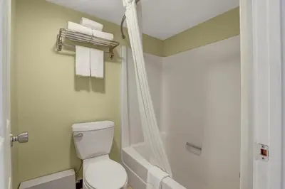 a bathroom with a toilet and a shower with towels at Motel 6 Brooks AB in Brooks