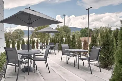 a patio with tables and chairs and an umbrella at Fairfield Inn & Suites by Marriott Penticton in Penticton
