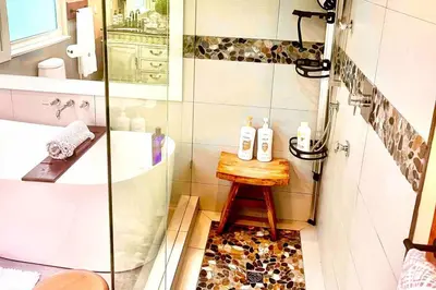 a bathroom with a shower and a stool next to a tub at Corkscrew Willow Estate in Vancouver