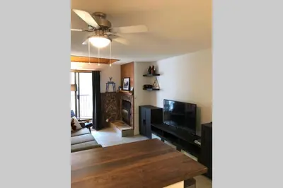 a living room with a table and a ceiling fan at Mountain Edge Ski-in Ski-out Condo in Kimberley