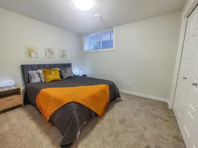 a bedroom with a bed with an orange blanket at GlobalStay Cranbrook Townhome Suites in Calgary