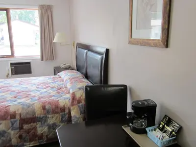 a hotel room with a bed and a desk with a chair at Monte Carlo Motel in Barrière