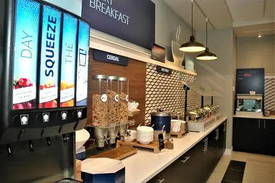 a coffee shop with a counter with food on it at Holiday Inn Express & Suites - Edmonton SW – Windermere by IHG in Edmonton