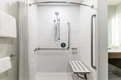 a white bathroom with a shower and a bench at Holiday Inn Express & Suites Edmonton N - St Albert by IHG in St. Albert