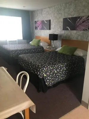 a hotel room with two beds and a table at Almada Inn in Fort Nelson