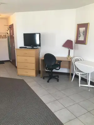 a room with a desk and a chair and a television at Almada Inn in Fort Nelson