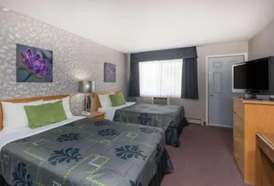 a hotel room with two beds and a flat screen tv at Almada Inn in Fort Nelson