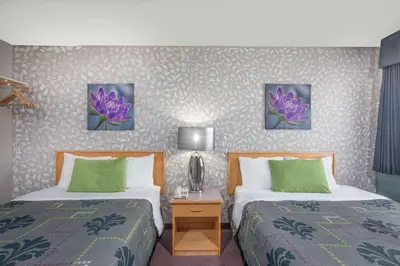 a hotel room with two beds with green pillows at Almada Inn in Fort Nelson