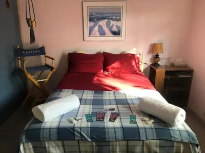 a bedroom with a bed with a red comforter at Queen, walk to village center in Whitehorse