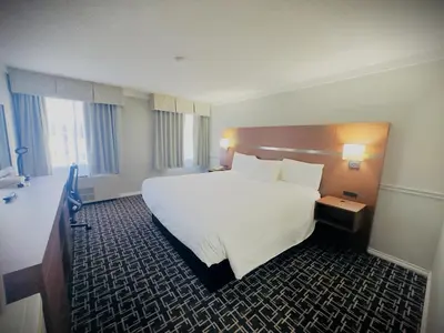 a hotel room with a large white bed and windows at Baymont by Wyndham Edson in Edson