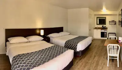 a hotel room with two beds and a kitchen at Humpback Inn in Port McNeill