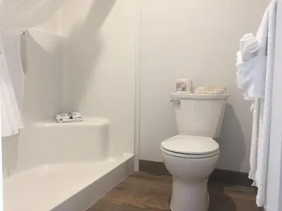 a white bathroom with a toilet and a bath tub at Humpback Inn in Port McNeill