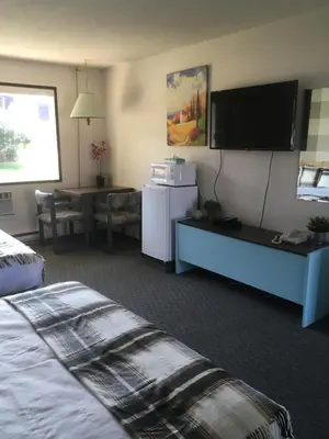 a hotel room with a bed and a flat screen tv at Christina Lake Motel and RV Park in Christina Lake