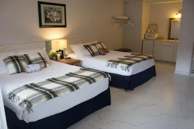 two beds in a hotel room with a kitchen at Christina Lake Motel and RV Park in Christina Lake