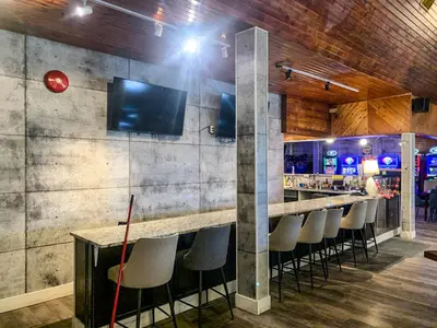 a bar with stools and a television on a wall at 7 Day's Hotel in Lamont