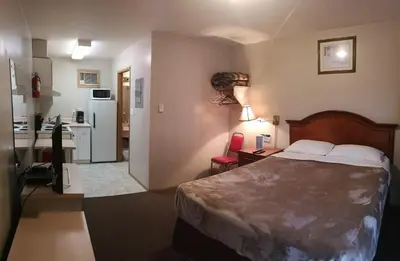 a hotel room with a bed and a kitchen at Ranchland Villa Motel in Merritt