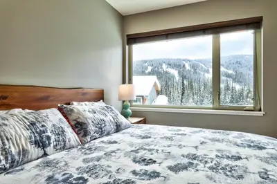 a bedroom with a bed and a large window at Echo Landing#02 By Bear Country in Sun Peaks