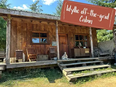 a dog sitting in front of a log cabin at Maple Heart Ranch in Shawnigan Lake