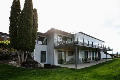 a white house with a balcony and trees at The Inn at Therapy Vineyards in Naramata