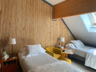 a hotel room with two beds and a chair at Ambleside Lodge Bed & Breakfast in Canmore