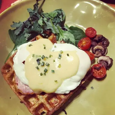 a plate of food with an egg on top of waffles at Ambleside Lodge Bed & Breakfast in Canmore
