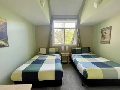 two beds in a small room with a window at Renovated Chalet at Mystic Springs, Mountain Views, Pets Welcome! in Canmore