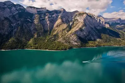 a body of water with a boat in front of a mountain at North House - Banff Mountain Home- The Real Rockies Experience in Banff
