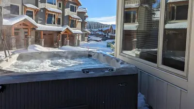 a hot tub on a balcony with snow on the ground at Echo Landing #12 by Bear Country in Sun Peaks