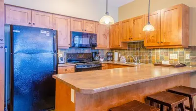 a kitchen with a blue refrigerator and wooden cabinets at Settlers Crossing #61 by Bear Country in Sun Peaks
