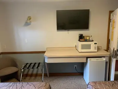 a room with a desk with a microwave and a tv at Peaks Lodge in Revelstoke