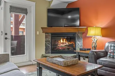 a living room with a fireplace with a tv on the wall at Sophisticated MTN 2 Bedroom Pool Hot Tub managed by Little Sister Getaways in Canmore