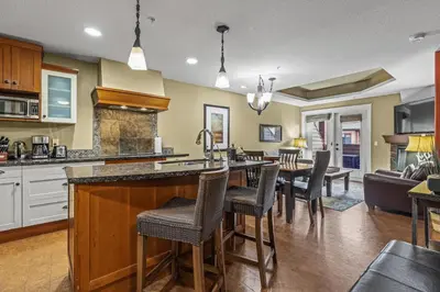 a kitchen and living room with a bar and chairs at Sophisticated MTN 2 Bedroom Pool Hot Tub managed by Little Sister Getaways in Canmore