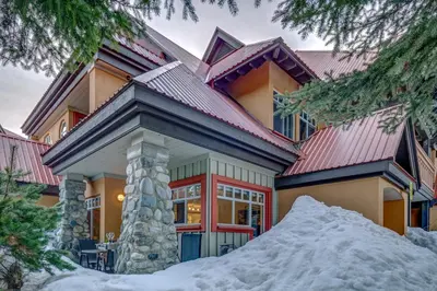 a house in the winter with a pile of snow at Sunpath Retreat- Convenience Meets Comfort & Style in Whistler