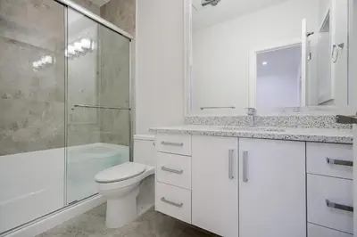 a white bathroom with a toilet and a shower at Sun suite in Surrey