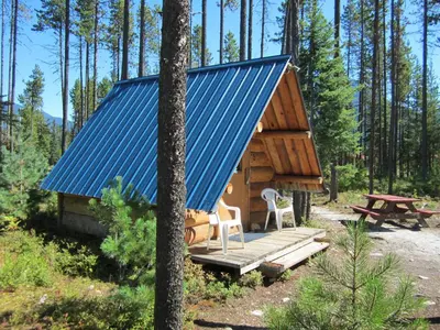 a cabin in the woods with a blue roof at Blue River Campgrounds & Cabin-public washroom in Blue River