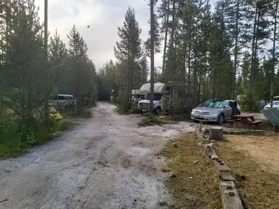 a dirt road with a car and a camper on it at Blue River Campgrounds & Cabin-public washroom in Blue River