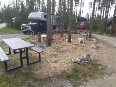a park with a picnic table and a truck in the woods at Blue River Campgrounds & Cabin-public washroom in Blue River
