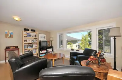 a living room with black leather furniture and a window at Heron View Cottage by EMR Vacation Rentals in Sidney