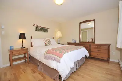 a bedroom with a bed and a dresser and a mirror at Heron View Cottage by EMR Vacation Rentals in Sidney