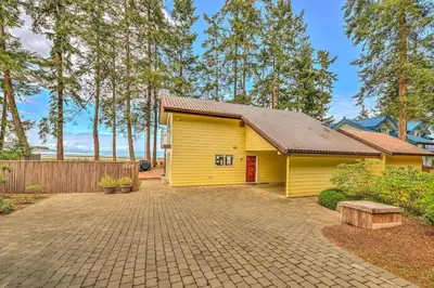 a yellow building with a driveway in front of it at Kye Bay Beach House by EMR Vacation Rentals in Comox