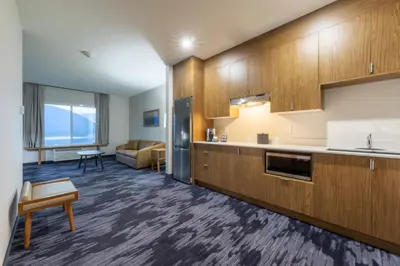a kitchen with wooden cabinets and a living room at Fairfield Inn & Suites by Marriott Salmon Arm in Salmon Arm